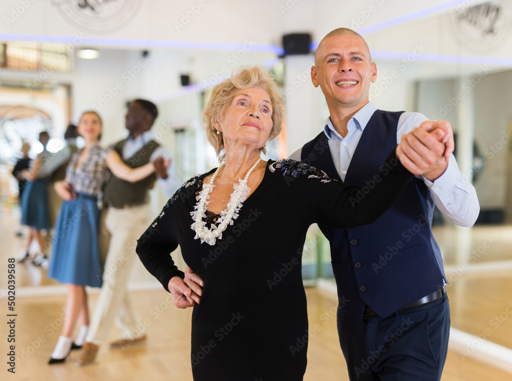 Elderly woman learning ballroom dancing movements in pair - obrazy, fototapety, plakaty 