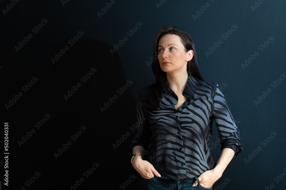 portrait of a young serious brunette on a dark studio background portrait of a young serious brunette on a dark studio background