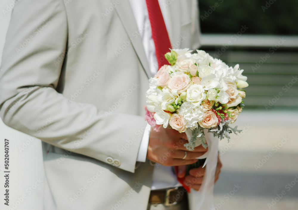 Beautiful delicate wedding bouquet of the bride in the hands of the groom Beautiful delicate wedding bouquet of the bride in the hands of the groom