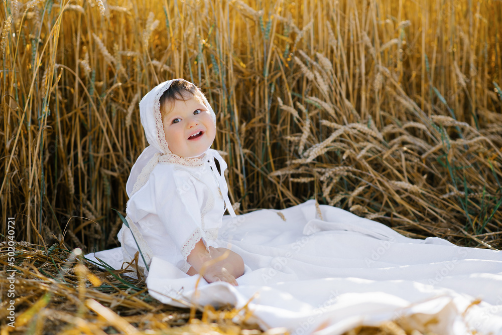 Sweet eight-month-old baby boy sitting on a blanket in a field and laughing Sweet eight-month-old baby boy sitting on a blanket in a field and laughing