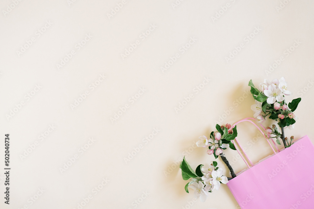 Apple tree flowers in a shopping bag on a biege background with copy space. Top view and flat lay. The concept of spring discounts in stores.
