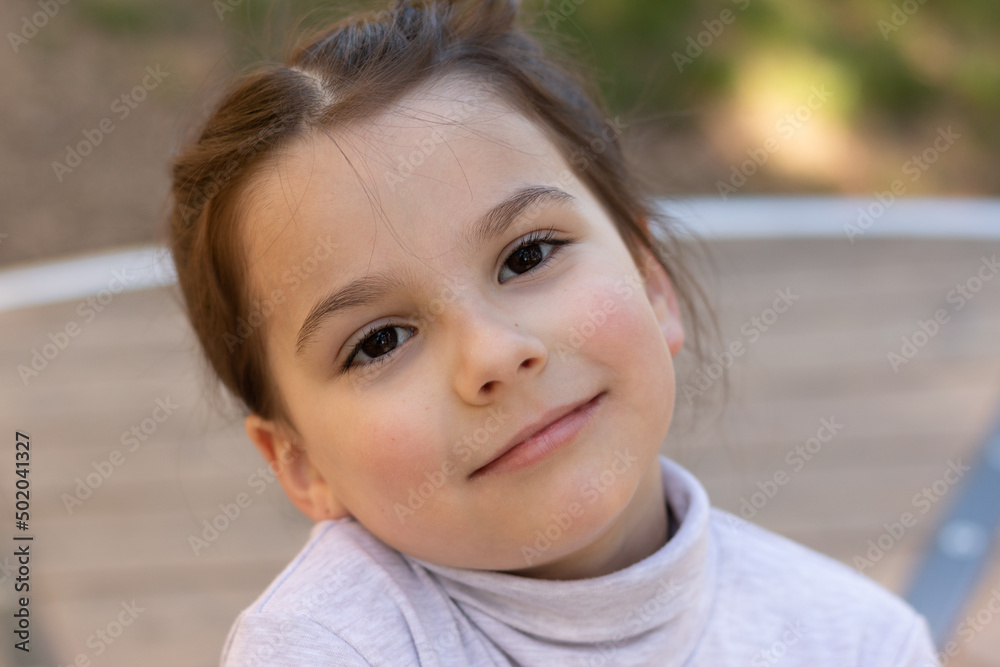 Close-up portrait of a little beautiful girl in a turtleneck sweater in the park Close-up portrait of a little beautiful girl in a turtleneck sweater in the park