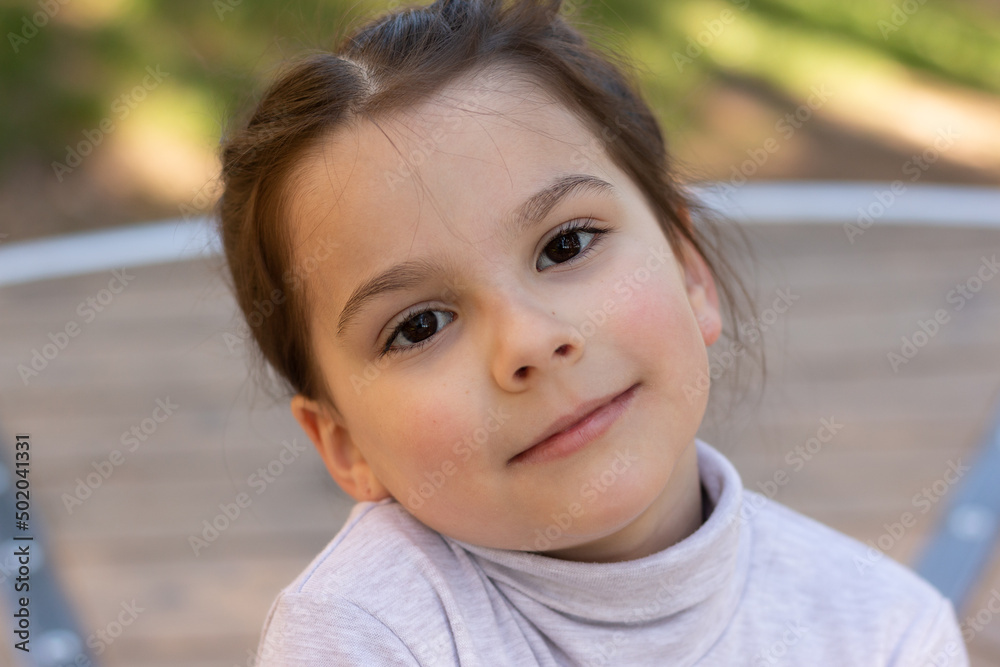 Close-up portrait of a little beautiful girl in a turtleneck sweater in the park Close-up portrait of a little beautiful girl in a turtleneck sweater in the park