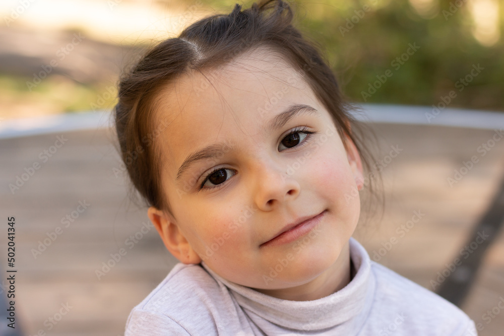 Close-up portrait of a little cute girl in a turtleneck sweater on the street Close-up portrait of a little cute girl in a turtleneck sweater on the street