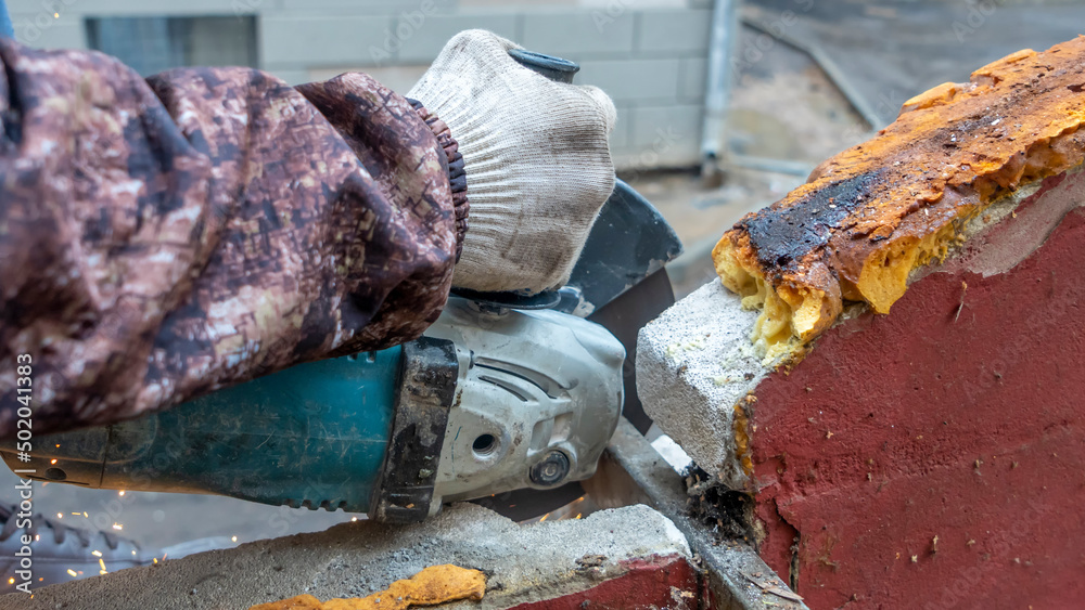 Obraz premium Close-up view of a worker working with angle grinder. Electric wheel grinding on steel structure. Sparks.