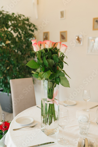 A bouquet of beautiful white pink roses in a glass vase on the banquet table