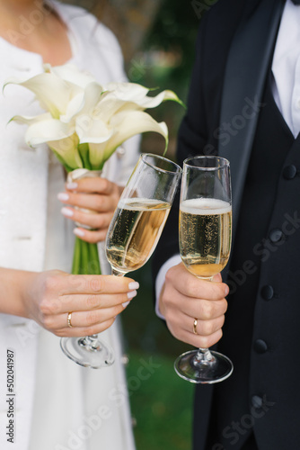 Close-up of the hands of the bride and groom with glasses of champagne