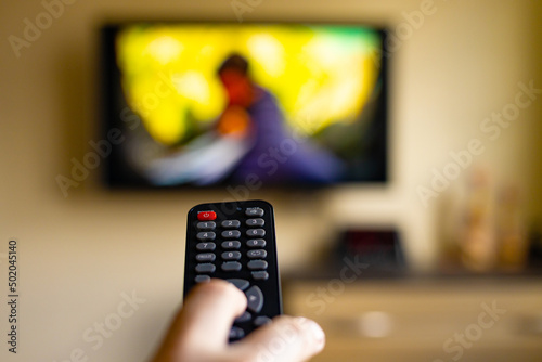 Television watching concept with remote control in hand. Close-up, selective focus