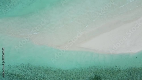 Sandbank beach with beautiful water waves texture. Abstract background for vacation holiday travel with white sand and blue sea. Top down aerial drone video footage. 4k 60 fps.