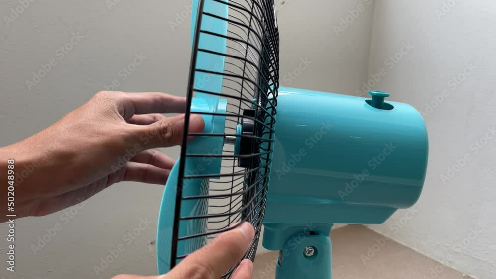 Tighten black plastic nut at blue blade electric fan. Hand fasten bolt