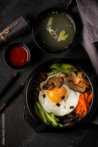 Korean dish bibimbap with broth on a dark background. View from above