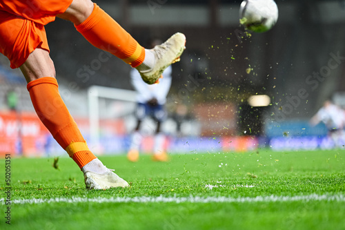 Football player's legs and blades of grass flying after kicking the ball during soccer match. © Dziurek