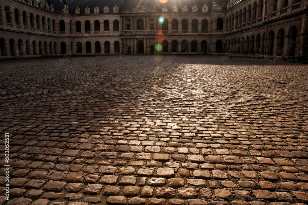 The courtyard of the palace paved with paving stones in the evening light. Louvre. Paris.