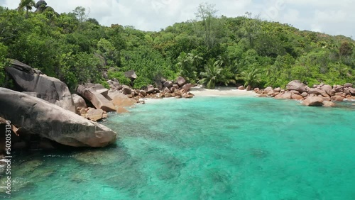 Aerial dolly slowly to small white beach lost between granite boulders