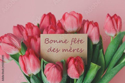 craft gift card with the inscription happy mother s day in french in a bouquet of bright beautiful tulips, the concept of congratulations on the holiday photo