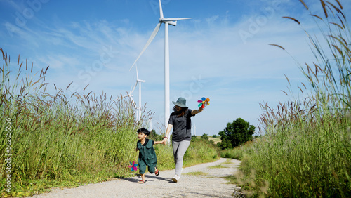 Mother and his son run around with windmills in a wind turbine field, mother teaching his son how to live in harmony with nature and technology, family relationships.