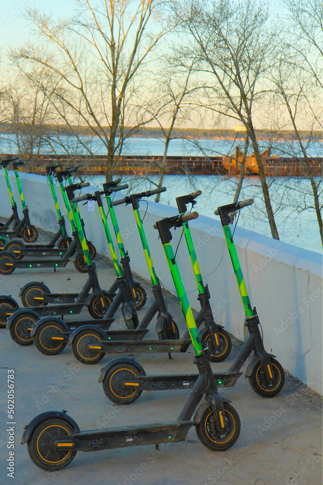 Street electric scooters are lined up on the city embankment. The concept of urban transport