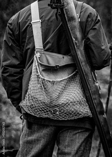 The back of a huntsman with his game bag and shotgun in its sleeve over his shoulder.