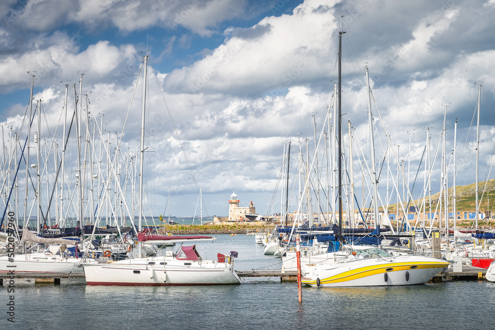Howth lighthouse seen through masts of sailboats, yachts and motorboats moored in Howth marina, Dublin, Ireland