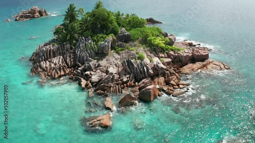 Aerial crane tilt down at tiny islet St. Pierre with granite and palms
