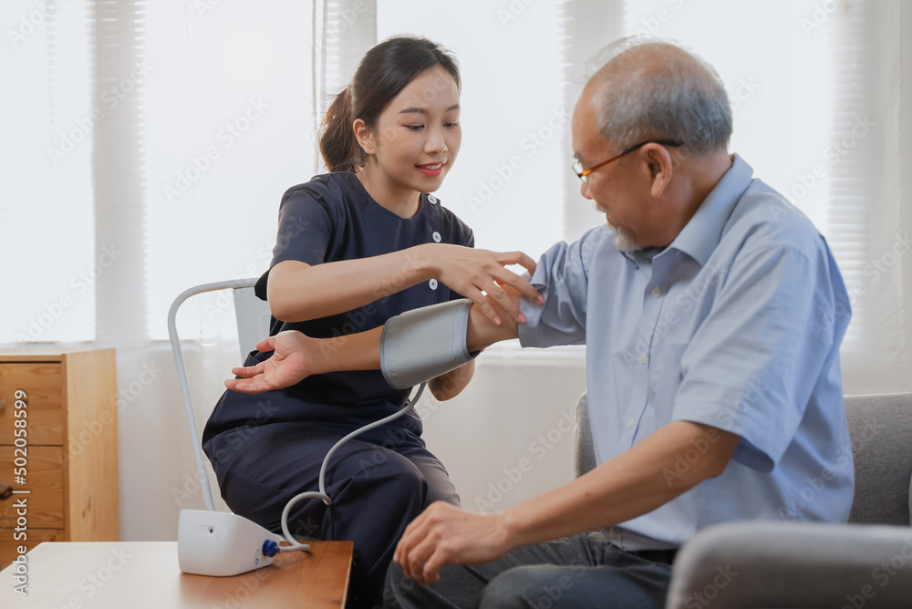 Obraz premium Nurse care service for retirement people, professional female caregiver measuring blood pressure senior man at home.