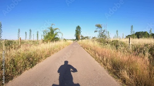 Camino Torres, shadow of a touring cyclist riding on a secondary paved road leaving Ciudad Rodrigo, province of Salamanca, Castile and Leon, Spain - dolly photo