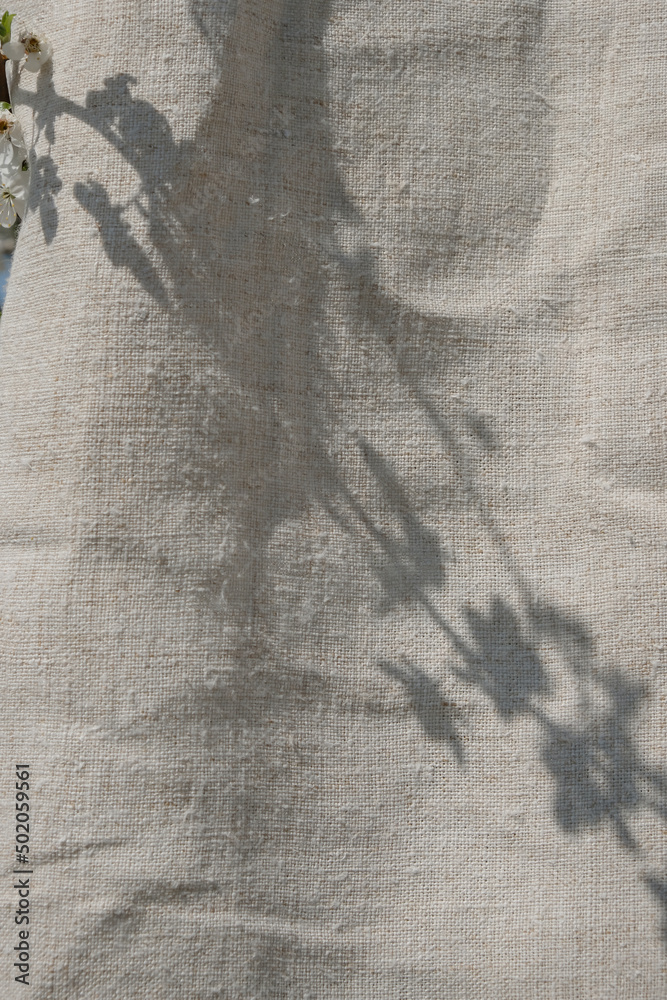 Hemp fabric. Shadow from a flowering branch on a fabric background. Environmentally friendly textile. Vertical image. 