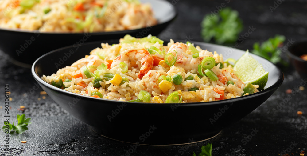 Prawn fried rice with eggs and vegetables in black bowl. Healthy asian food. Prawn fried rice with eggs and vegetables in black bowl. Healthy asian food.