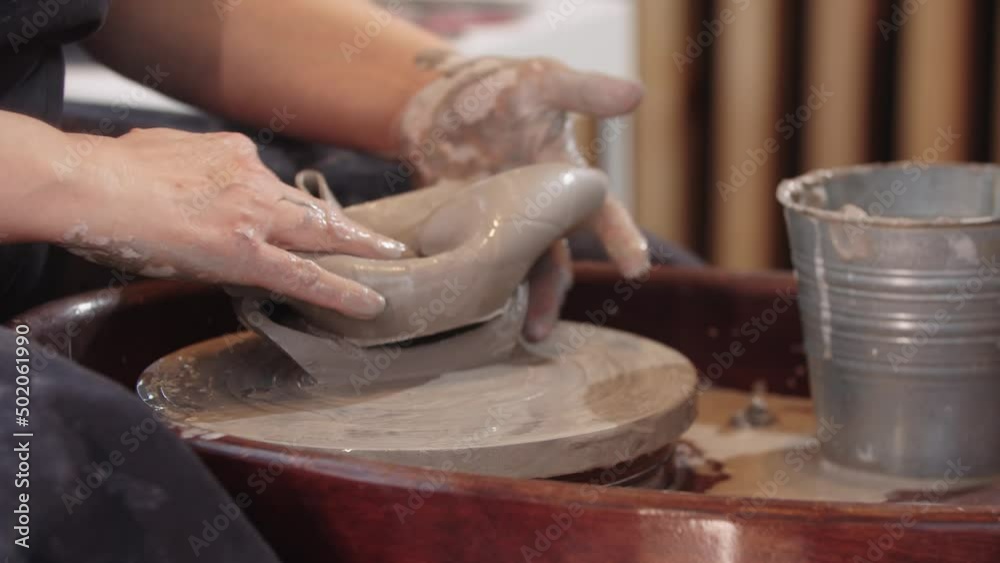 An elderly woman potter reshaping soft piece of clay