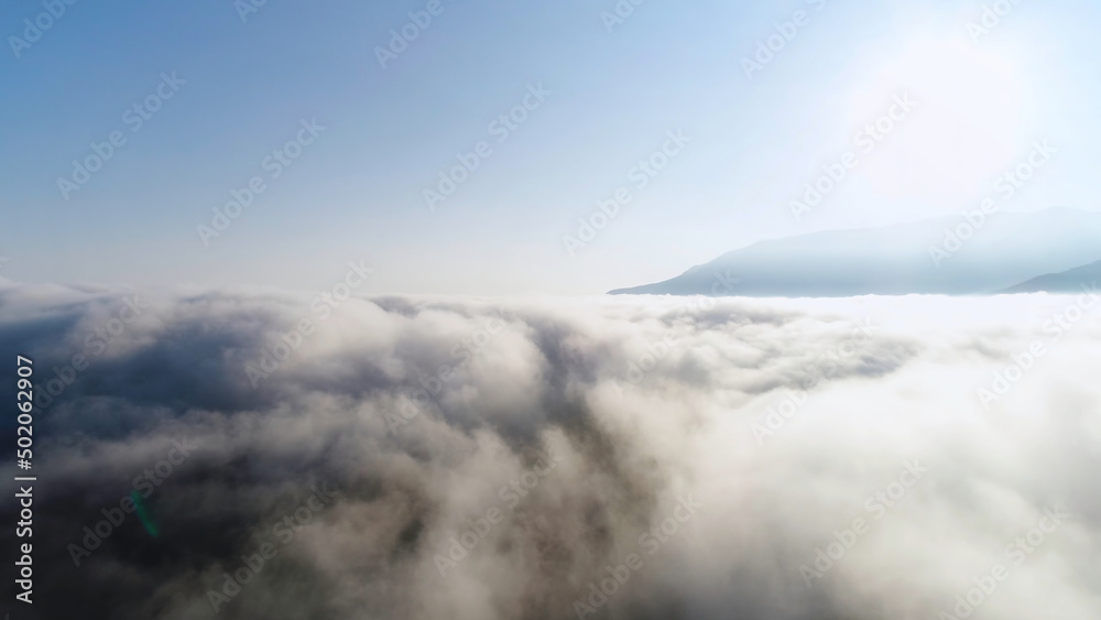 Beautiful endless heaven, bright sun and blue, clear sky. Shot. Breathtaking view of white clouds flowing against mountain tops and blue sky in the morning.