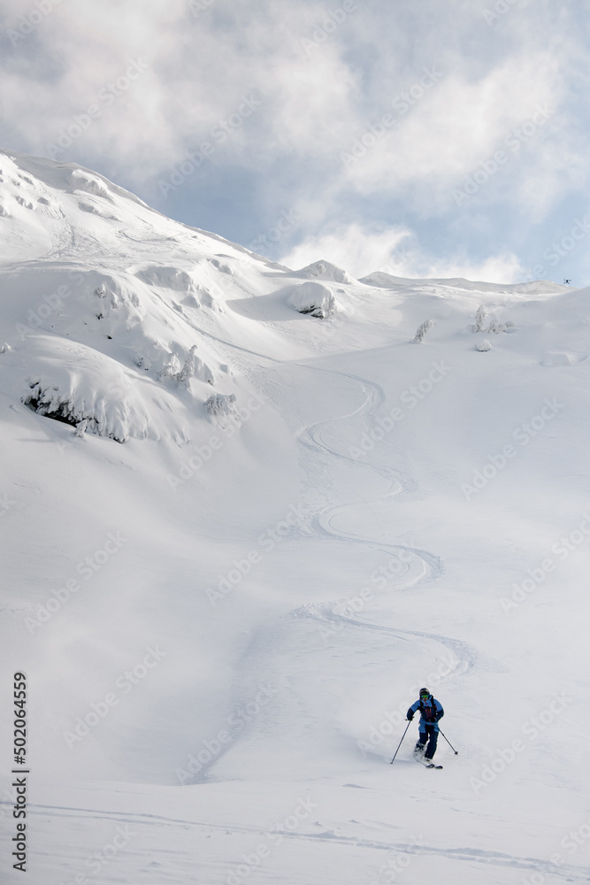 Athletic snowboarder ride down the untouched powder snow. Picturesque snow covered mountain scenery surrounds