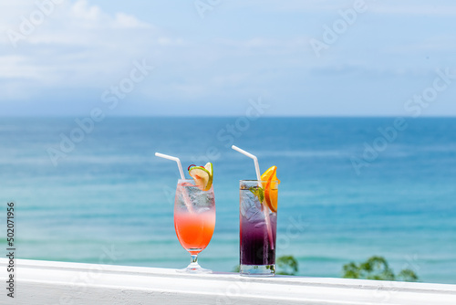 Fresh cold iced cocktail on bar with tropical beach and blue sea view at hot sunny day. Summer sea vacation and travel concept in Thailand