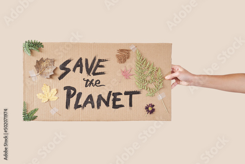 Hand holds a handmade cardboard with an inscription: Save the planet.
