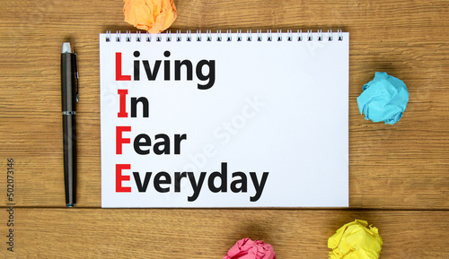 LIFE living in fear everyday symbol. Concept words LIFE living in fear everyday on the note on a beautiful white background. Business LIFE living in fear everyday concept. Copy space. © Dzmitry