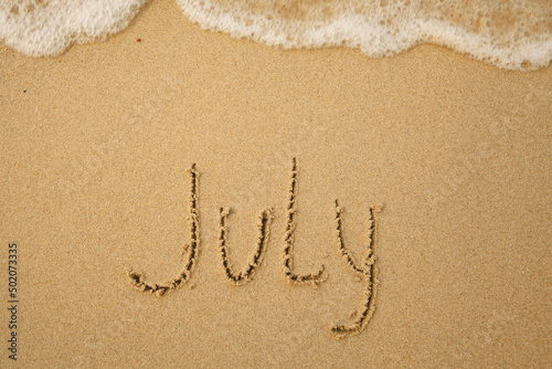 July - handwritten on the soft beach sand. © De Visu