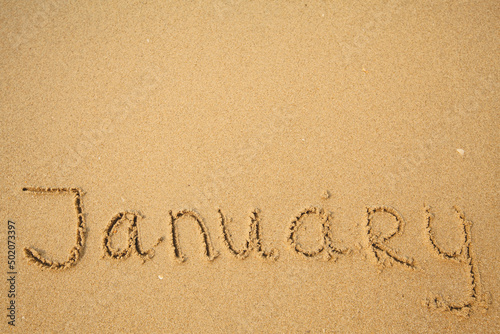 January - handwritten on the soft beach sand.