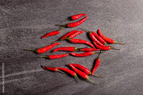 A handful of red bird's eye chili on black background, top view.