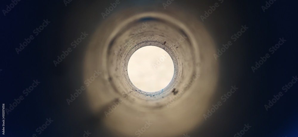 Close-up deep endless round large and long concrete pipe hole with blurry  black foreground and white background with copy space. Bore well, drainage,  pipeline, mining and factory sewage concept. Photos | Adobe