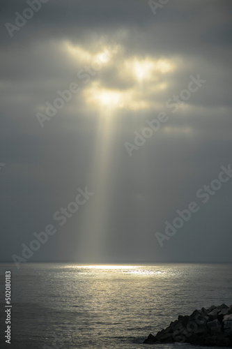 the golden rays of the sun pierce the gloomy gray clouds over the water. the rays of the sun over the ocean in Portugal  Ericeira