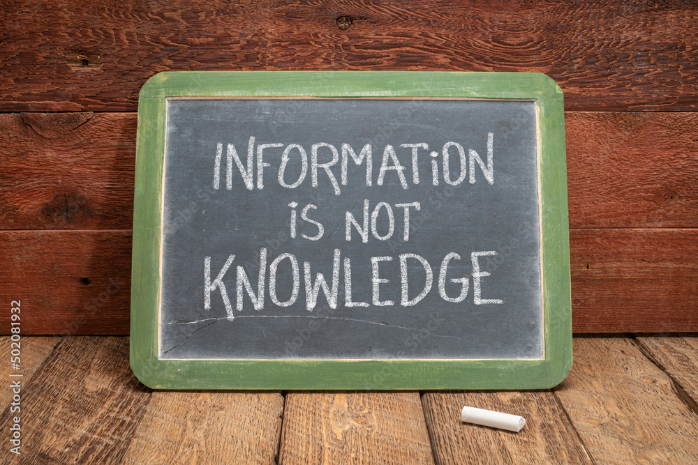 Fototapeta premium information is not knowledge quote - white chalk text on a vintage slate blackboard against rustic wood, education, science and communication concept