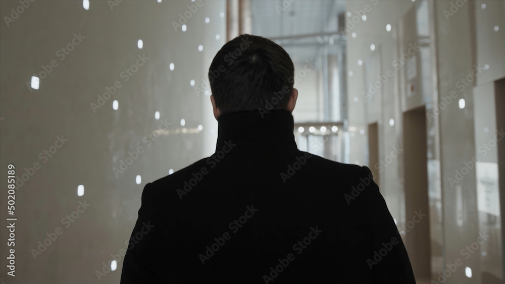 Back view of businessman walking in modern office building. Stock. The businessman stay in the business center