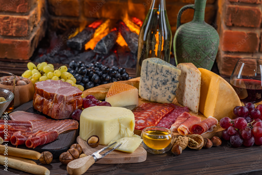 Charcuterie plate board, meat, boiled pork, smoked meats, prosciutto, and wine. Cheese pieces, nuts, grapes, honey on a wooden table. Refreshments and tasting alcoholic drinks in the wine cellar