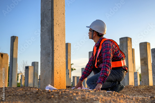 Fotografering Construction engineers survey checkpoints of concrete pile,  load-bearing piles of the tall building at the construction site evening time