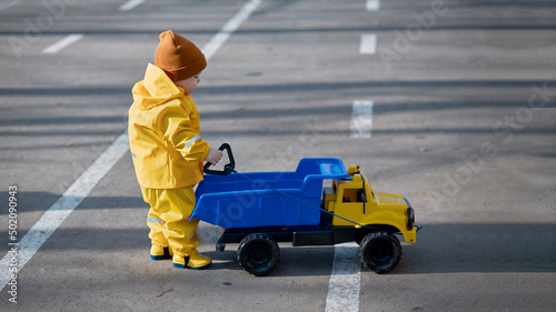 a little boy plays with a dump truck on the street
