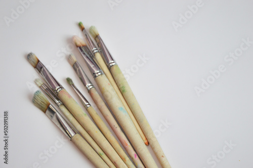 Brushes of different sizes with wooden handles and natural bristles on a white background. Free space for text.