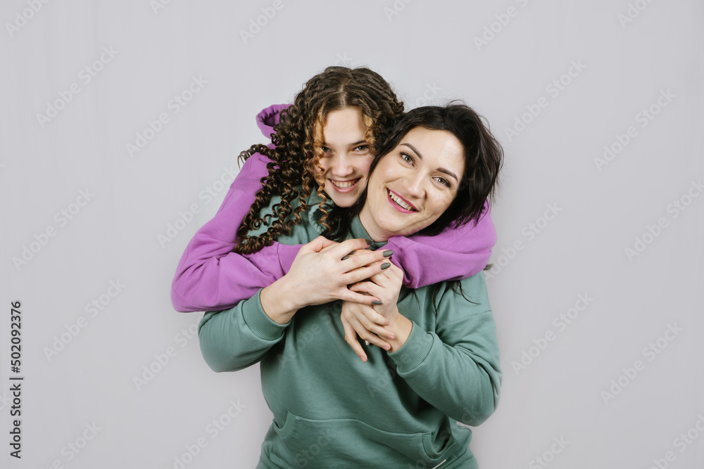 Portrait of happy mom and teen daughter spend time together. Teenage girl hugging her mother and having fun together Portrait of happy mom and teen daughter spend time together. Teenage girl hugging her mother and having fun together