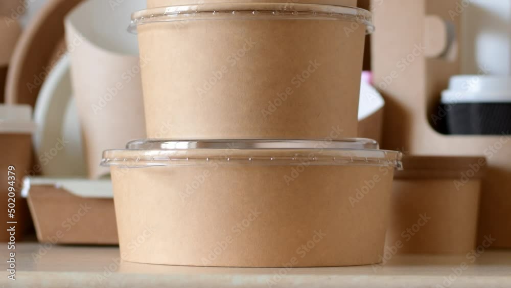 Paper biodegradable round containers for food on the background of paper disposable tableware. Camera movement vertically.