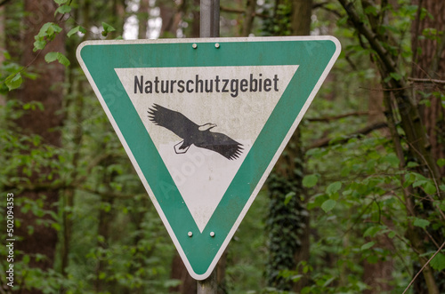 Dreiecksschild mit dem Schriftzug „Naturschutzgebiet“ und einem Adler auf weißem Grund
