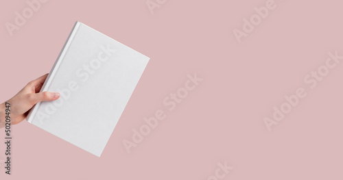 Fotografie Banner with hand holding book mockup on pink, pastel background