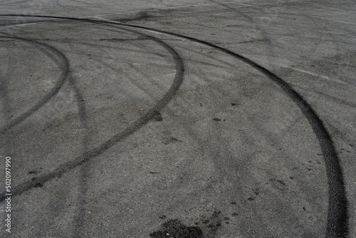 Asphalt texture with white line and tire marks. Smooth asphalt road. Tarmac dark grey grainy road background.Top view
